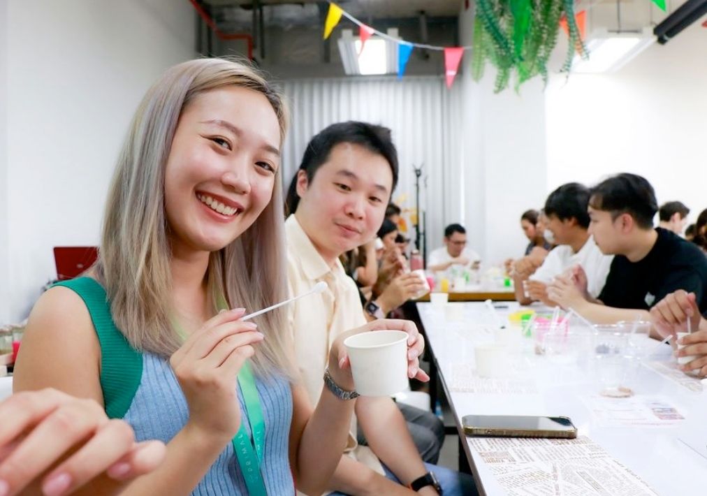 Two employees smiling at the camera during a workshop at a long table