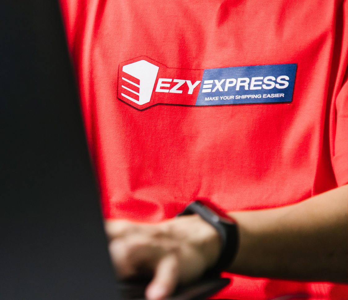 An employee in a red Ezy Express T-shirt working on a laptop