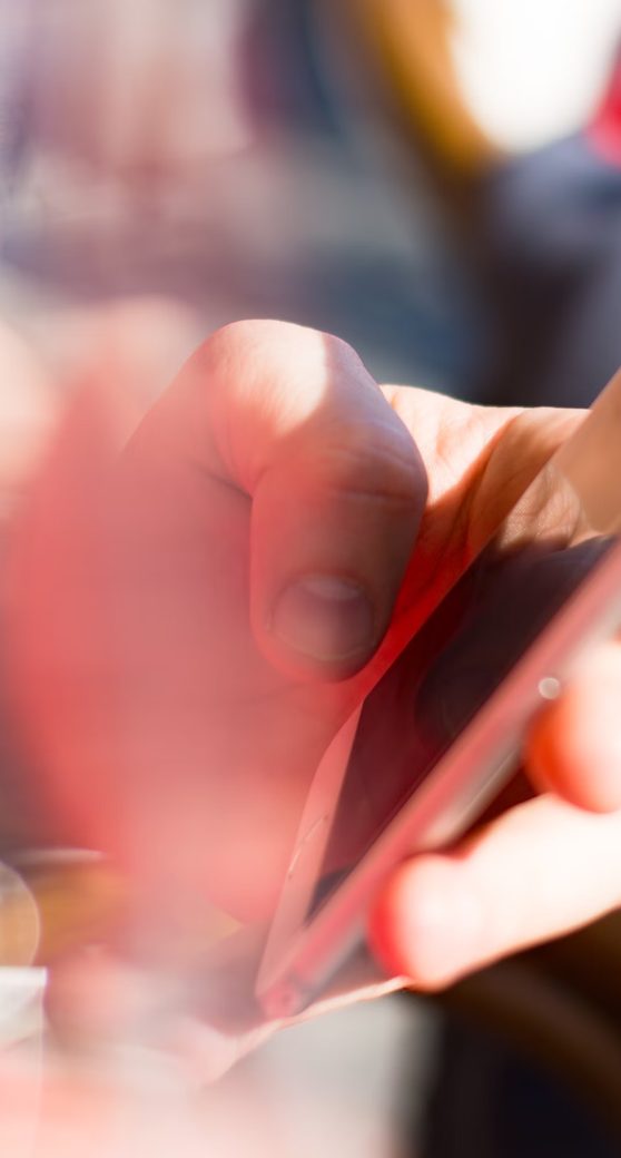 A hand using a smartphone, close up in red tones