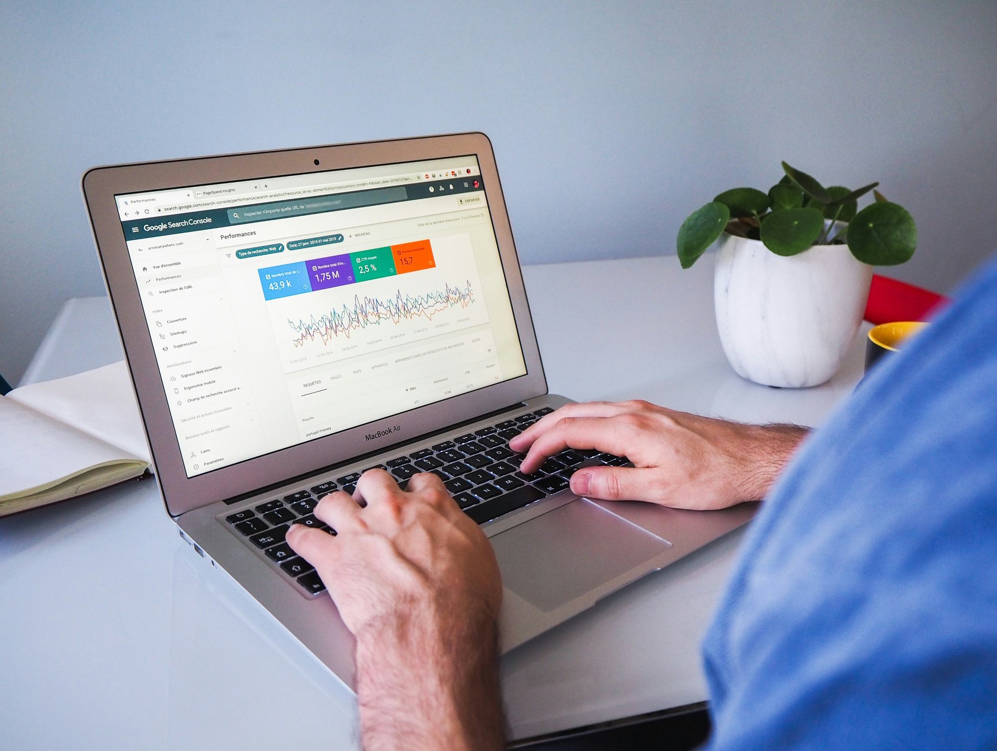 A hand typing on a laptop showing a search-performance dashboard