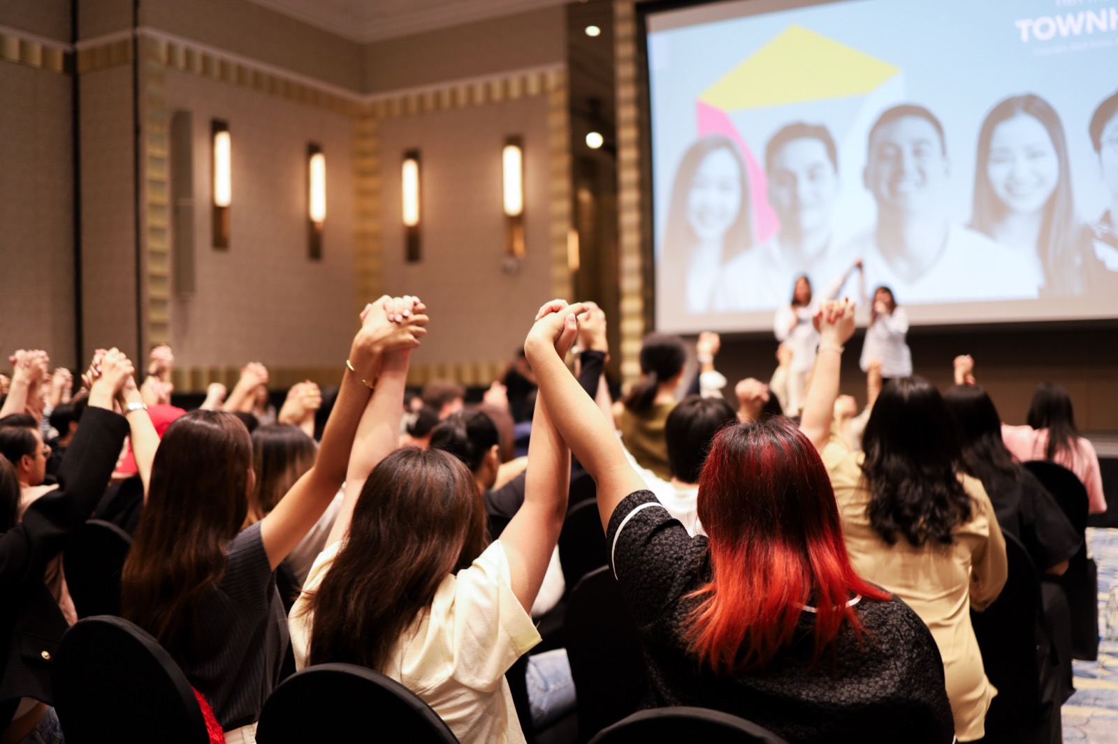 Guests raising clasped hands overhead in the awards announcement room